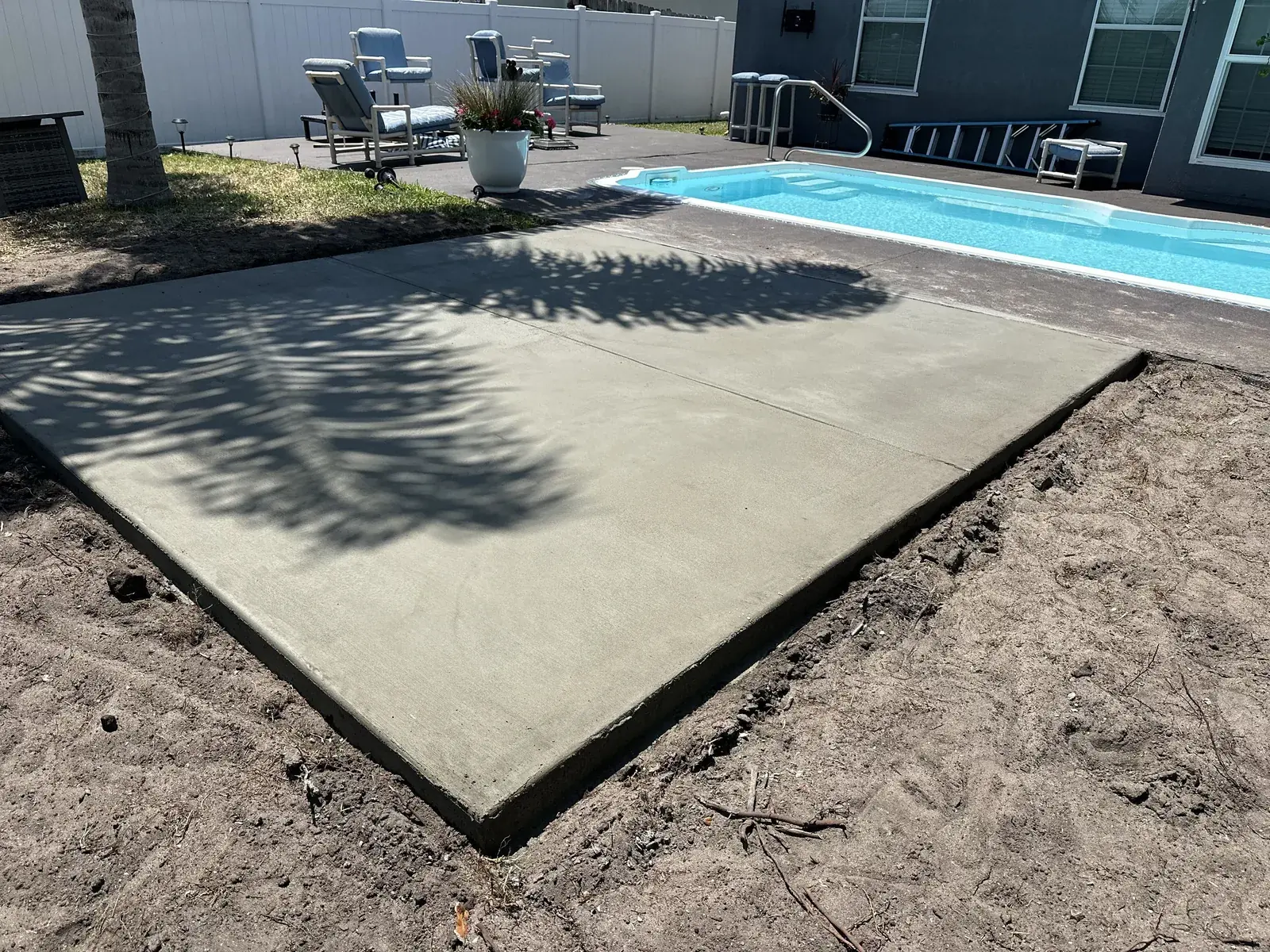 Plain broom finished concrete slab poured beside a backyard pool